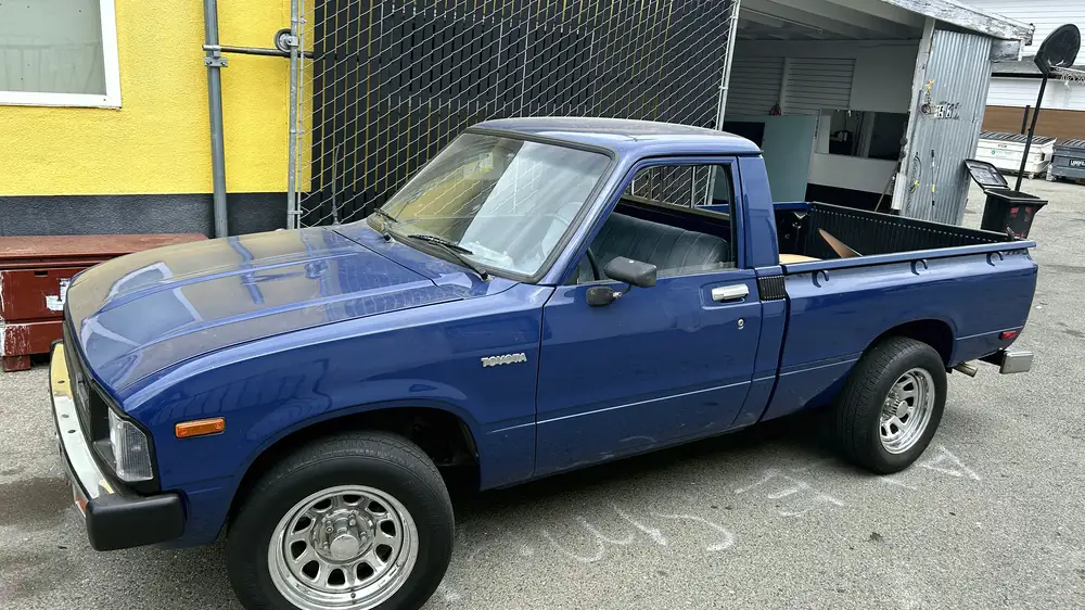 An early-eighties Toyota pickup, freshly painted blue, parked at the shop