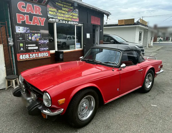 The owner's red 1976 Triumph TR6 parked in front of the shop
